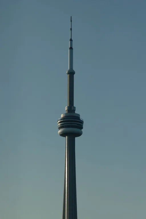 The CN Tower photographed from below against a clear blue sky, its observation pod and antenna centered in the frame.